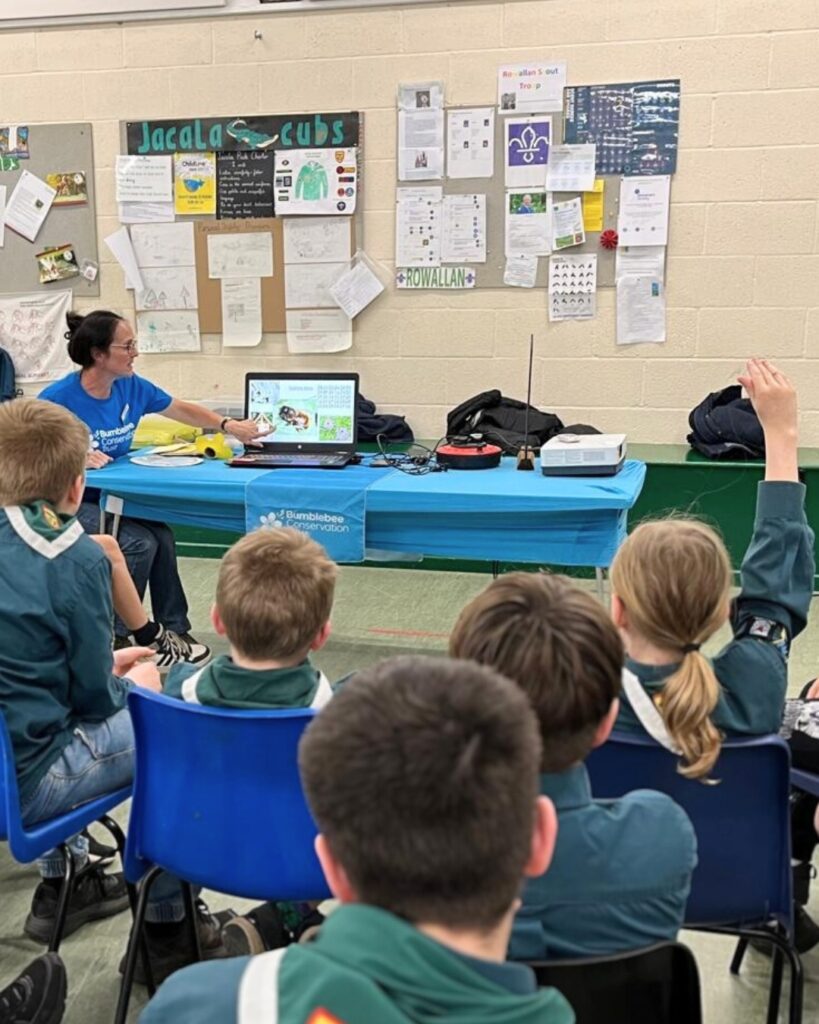 A woman delivers a bumblebee talk to a group of children.