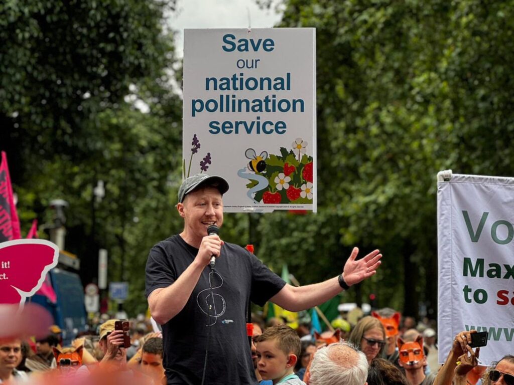 A campaigner addressing a crowd with a microphone at a peaceful demonstration.